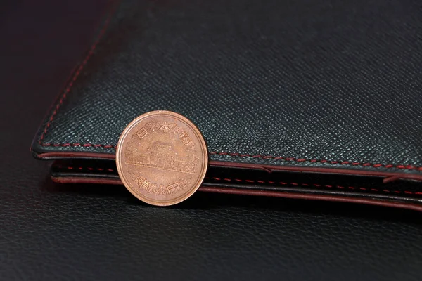 Siyah zemin üzerinde siyah cüzdanı olan on Japon Yen (JPY) madeni para, finans kavramı.