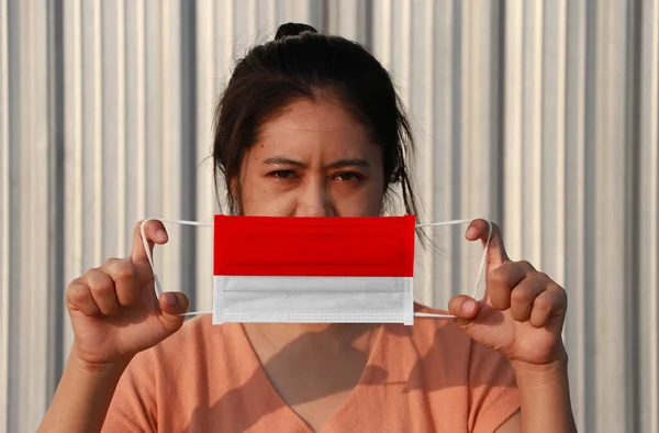 一名妇女手持卫生面具 手持印度尼西亚国旗 在灰色背景下抬起前脸 微小颗粒或病毒电晕或Covid 19保护 防治疾病的概念 — 图库照片