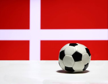 Beyaz zeminde küçük bir futbol topu ve Danimarka bayrağının arka planında beyaz haç. Spor konsepti.