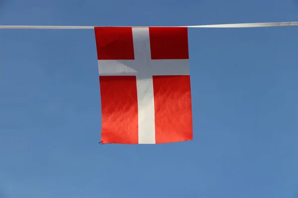デンマークのミニファブリックレールの旗は 青い空の背景にロープの布にかかって 旗の端にまで及ぶ白い北欧の十字架と赤です — ストック写真