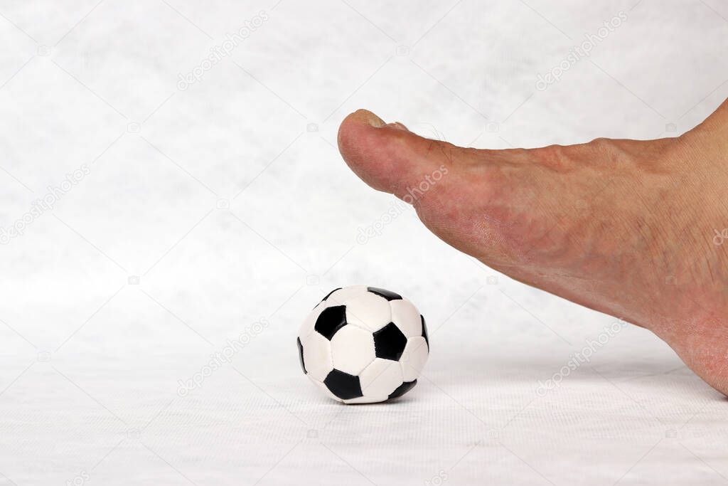 Mini ball of football on the floor under the foot with white background. Concept of sport.