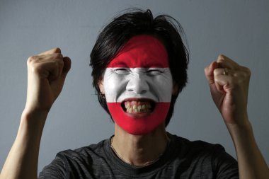 Gri arka planda Avusturya bayrağı taşıyan bir adamın neşeli portresi. Spor ya da milliyetçilik kavramı. 