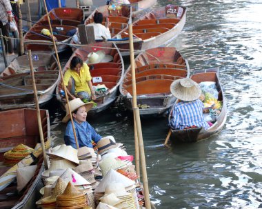 Damnoen Saduak, Ratchaburi, Tayland - 31 Aralık 2018: Şapka satıcısı teknesinde oturuyor ve Damnoen Saduak yüzen pazarındaki kanalda birçok tekne.