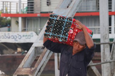Yangon, Myanmar, 24 Şubat 2019: Myanmese işçisi gemiden kalkan bir sandıkla ördek yumurtaları taşıyor ve Yangon Nehri 'ndeki liman köprüsünü geçiyor..