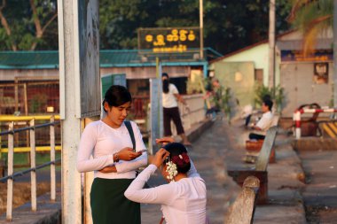 Yangon, Myanmar 25 Şubat 2019: Geleneksel elbiseli iki Myanmarese 'li kadın, cep telefonunu kontrol eden bir kişi ve Yangon' da çiçekli bir saç modeli.