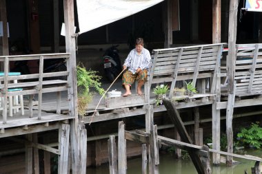 Lat Lum Kaeo, Pathum Thani, Tayland, Sep 9, 2019: Rahang Kanalı 'ndaki eski ahşap terasta oturan ve balık tutan kadın.