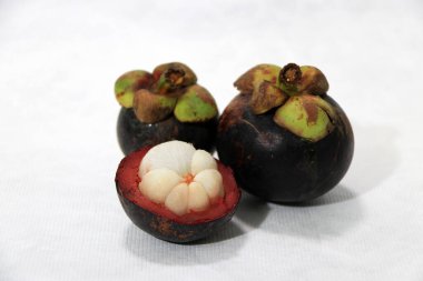 İki mangosteen ve beyaz arka planda bir kabuk. Meyve kraliçesi..