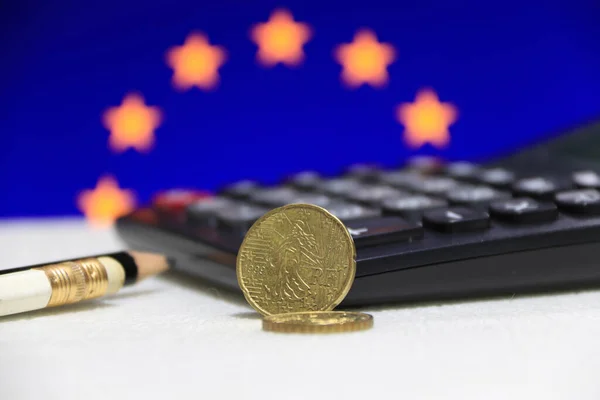 Twenty France euro cent on obverse on white floor with black calculator and pencil, European Union flag background, the concept of finance.