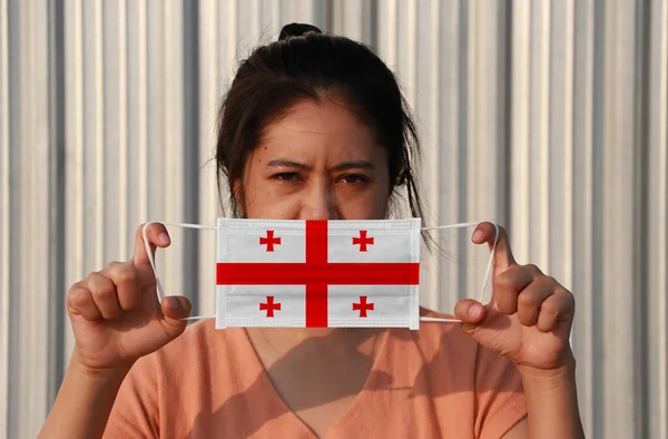 一位手上拿着格鲁吉亚国旗 戴着卫生面具的妇女 在灰色背景下抬起了前面的脸 微小颗粒或病毒电晕或Covid 19保护 防治疾病的概念 — 图库照片
