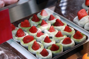 Çilekli yeşil çay aromalı Mochi bardağın içindeki tepside satılık. Mochi, Japon mutfağında yüksek nişasta içerikli, kısa taneli, tatlı ve glutinöz bir pirinçtir..