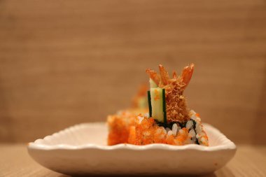 Kızarmış karides tarifi suşi yumurta karidesinde beyaz dikdörtgen tabakta ahşap zeminde..