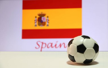 Beyaz zeminde küçük bir futbol topu ve İspanya arka planında İspanyol bayrağı. Spor konsepti, İspanya dünyadaki futbol turnuvasının finalistlerinden biridir..
