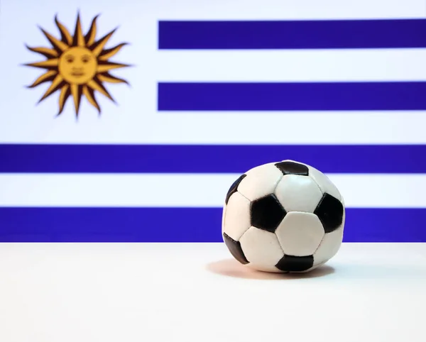 白色地板上的小足球和乌拉圭国旗背景 乌拉圭是世界足球锦标赛决赛的决赛者之一 — 图库照片