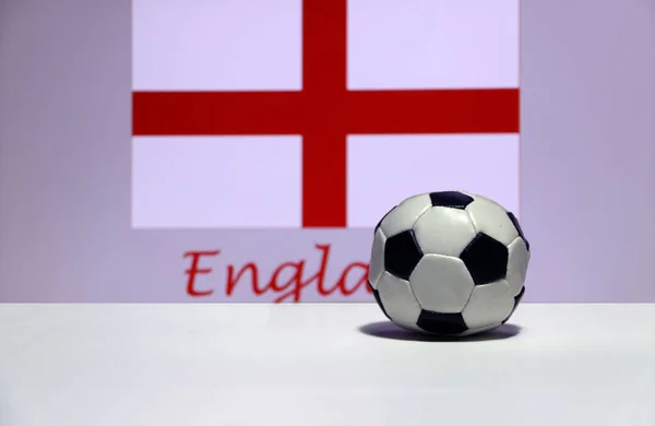 Small football on the white floor and English nation flag with the text of England background. The concept of sport, England is one of the finalists in football tournament of the world.