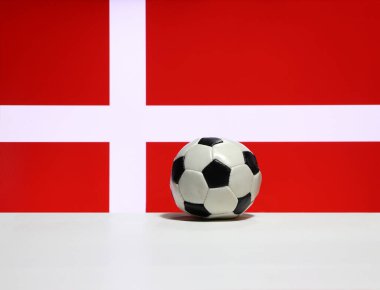 Beyaz zeminde küçük bir futbol topu ve Danimarka bayrağının arka planında beyaz haç. Spor konsepti.