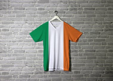 Gömlekte İrlanda bayrağı, duvarda tuğla desenli duvar kağıdı, yeşil beyaz ve turuncu. 