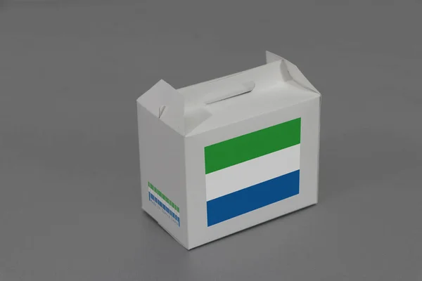 白色盒子上的塞拉利昂国旗有条形码 灰色背景上有国旗的颜色 塞拉利昂出口贸易的概念 用于产品的纸包装 — 图库照片