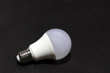 Siyah arka planda beyaz ampul. Lambaya ya da tavandaki bir sokete yerleştirilmiş cam bir ampuldür. Elektrik akımının içinden ya da gaz cebinden geçen bir ışık sağlar..