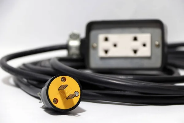 黄色插头和出焦点插座与黑色电缆的白色背景 用于电气连接 电气设备出口之间的长距离 — 图库照片