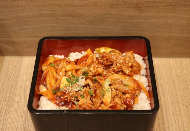 Ahşap zemindeki siyah kasede kimchi pilavlı kızarmış domuz eti..