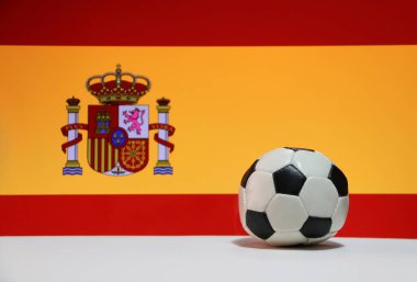 Beyaz zeminde küçük bir futbol topu ve İspanyol bayrağı arka planında. Spor konsepti, İspanya dünyadaki futbol turnuvasının finalistlerinden biridir..