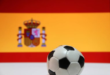 Beyaz zeminde küçük bir futbol topu ve İspanyol bayrağı arka planında. Spor konsepti, İspanya dünyadaki futbol turnuvasının finalistlerinden biridir..