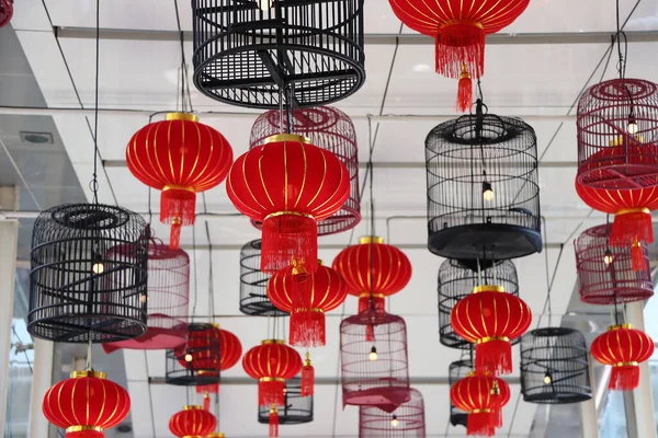 Red fabric lamps and bird cage lamps hanging on the ceiling. Welcome to the Chinese new year festival.