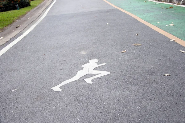 在与绿色自行车道平行的慢跑道上画的白人慢跑者 以平稳而温和的步伐跑步 尤指作为一种经常锻炼的方式 — 图库照片