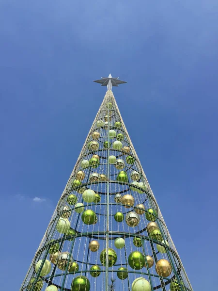 鋼で作られたクリスマスツリーは 青い空の背景を持つ昼の上にボールと星で飾られています — ストック写真