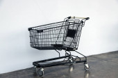 Černý nákupní košík na podlaze a bílé pozadí. vozík je vozík dodávaný obchodem, zejména supermarkety, pro použití zákazníky při přepravě na pokladní přepážku při nákupu.