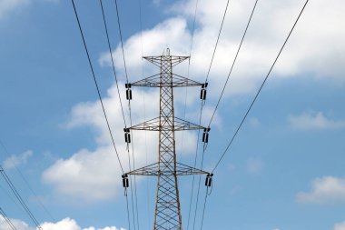 Mavi arka planda yüksek voltaj direği ve voltaj hattı var. çok fazla elektrik için büyük bir elektrik potansiyeli.