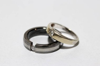Beyaz arka planda iki elmas yüzük. Küçük dairesel bir bant, tipik olarak değerli metalden yapılmış ve genellikle bir ya da daha fazla değerli taşla sabitlenmiş, parmağına takılmış bir süs ya da evlilik, nişan ya da otorite simgesi olarak..