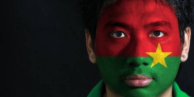 Siyah zemin üzerinde Burkina Faso bayrağı olan bir adamın portresi, sarı yıldızlı kırmızı ve yeşil..