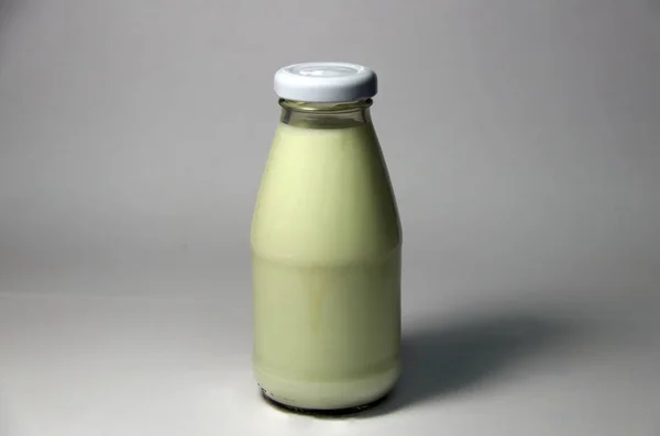 灰色の背景に白いキャップのミルクのボトル 灰色の背景に隔離されたガラス瓶の中の白い牛乳 — ストック写真