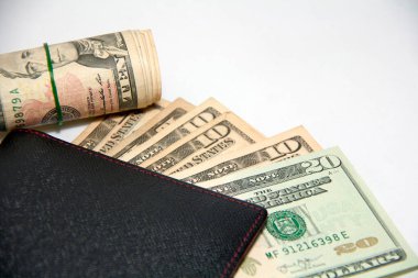 Amerikan paralı siyah cüzdan ve rulo banknotlar beyaz arka planda lastik bant kullanın, cüzdanda Amerikan doları banknotları.