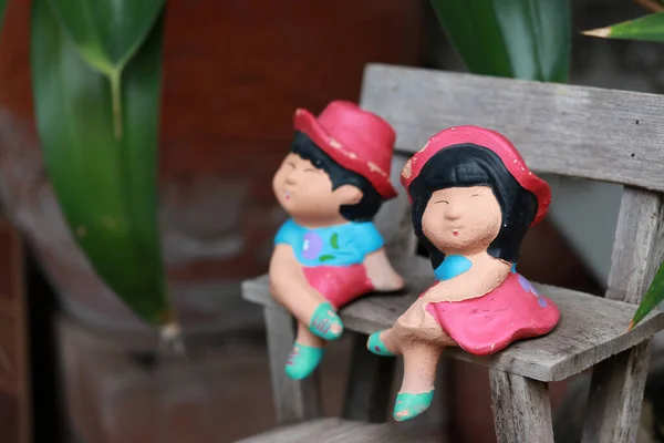 色彩艳丽的粘土娃娃男孩和女孩坐在小木制切斯特菲尔德上 小公园的装饰 — 图库照片