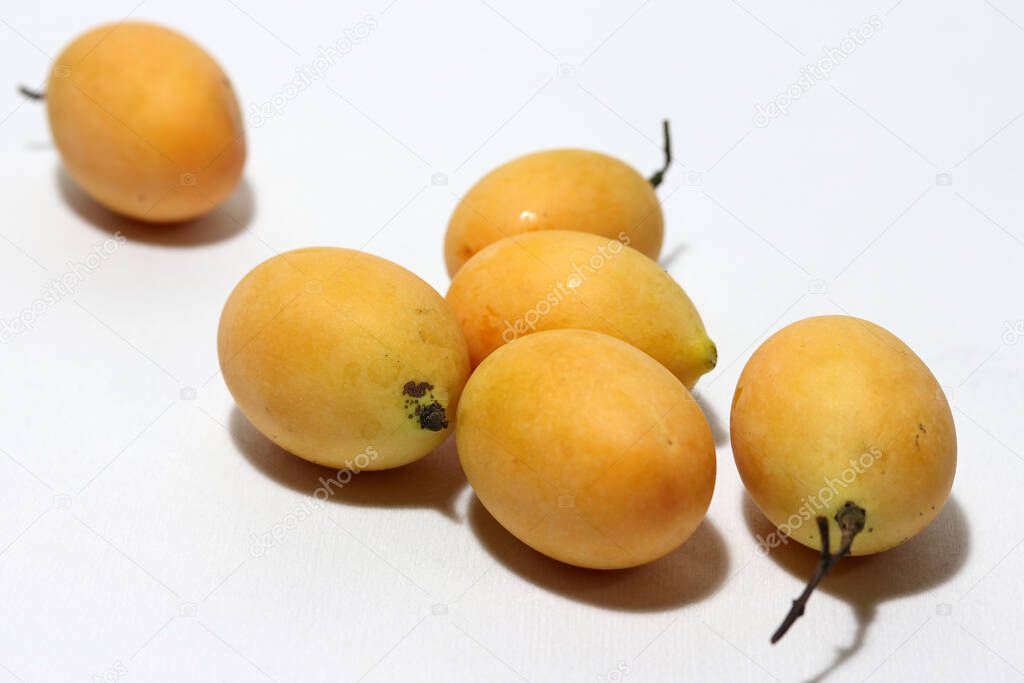 Bouea macrophylla, commonly known as gandaria put stack on white background. The orange color of fruit in tropical zone.