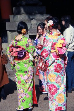 Fushimi-ku, Kyoto, Japonya, 17 Kasım 2017: Kyoto 'daki Fushimi Inari Tapınağı' nda kimonolu üç Japon kadının arkasında insanlar tapınak ya da tapınakta milli üniforma giyecek..