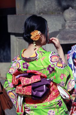 Fushimi-ku, Kyoto, Japonya, 17 Kasım 2017: Kyoto 'daki Fushimi Inari Tapınağı' ndaki Kimono elbiseli Japon kadının arkasında insanlar tapınak veya tapınakta ibadet etmek için ulusal üniformalar giyecekler.