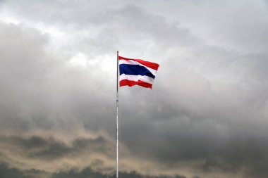 Arka planda Tayland bayrağı var. Yağmur yağarken gökyüzü kapalı..