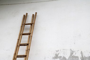 Bambu merdivenler duvara yaslanıyor. Beyaz havan duvarındaki merdivenler..