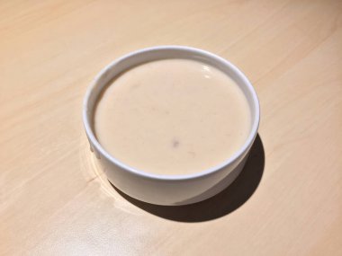 Krem rengi ahşap masadaki beyaz kasede çorba. Çorba, genellikle kaynamış et, balık ya da sebzelerle yapılan sıvı bir kasedir..