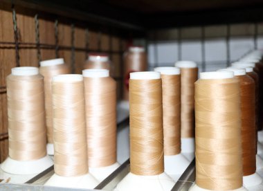 Rafta krem rengi iplik var. İpliğin bej rengi, dikiş dikmek için rafa dizilin.