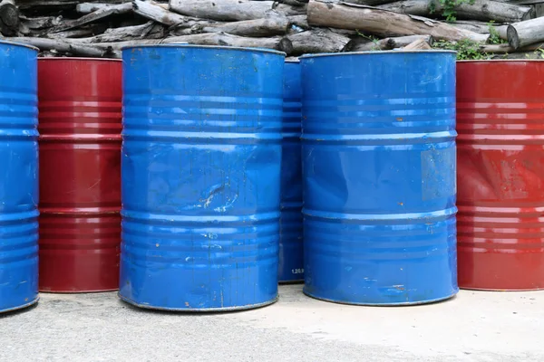 Empty tank of 200 liter fuel. blue and red color Put in front of old wood pile.