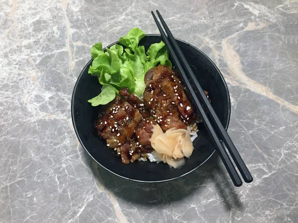 黒鉢に野菜と生姜を漬け込み豚肉を焼き 大理石のテーブルの上に黒箸で飾る — ストック写真