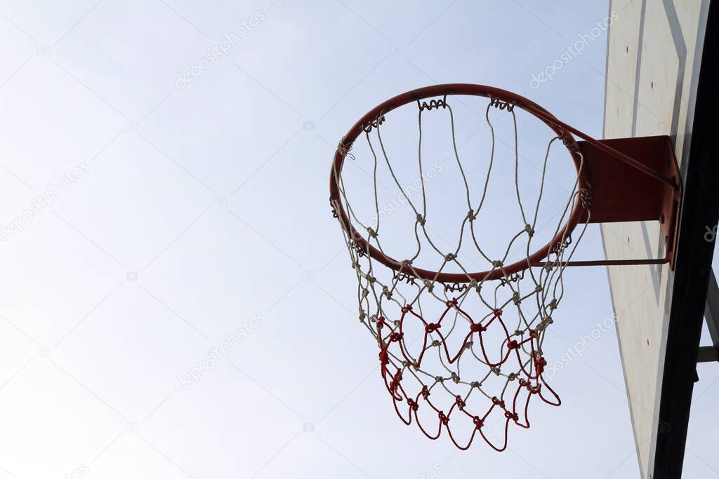 White board of basketball with red hoop and white-red mesh on the sky background. basketball is a game which goals are scored by throwing a ball through a netted hoop.