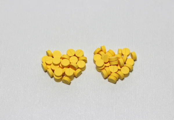 黄色の丸薬のカップルの山の中心部に白い床の上に形を置く 病院やバレンタインデーの愛の概念 — ストック写真