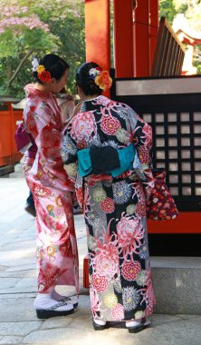 Fushimi-ku, Kyoto, Japonya, 17 Kasım 2017: Kyoto 'daki Fushimi Inari Tapınağı' ndaki turistler arasında kimonolu iki kadının arkasında insanlar tapınakta veya tapınakta ibadet etmek için ulusal üniformalar giyecekler.