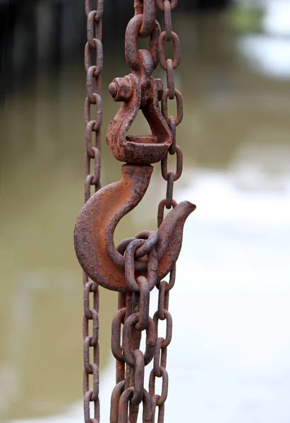 Antique rust of steel hook  carry steel chain and canal background. To gain weight of something heavy.
