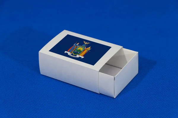 蓝色背景的白色盒子上挂着纽约国旗 从纽约进行出口贸易的概念 产品的纸包装 — 图库照片